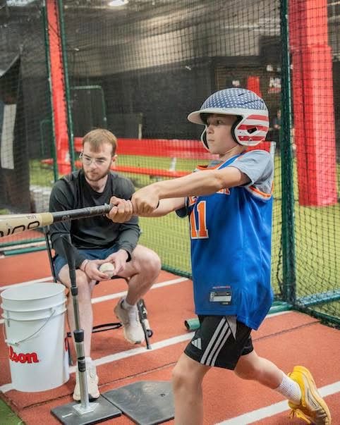 NexGen Sports coach helping a young athlete load and fire from the tee in the batting cage